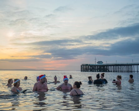 Swimmers, some in Santa hats, chatting in the sea on a beautiful winter’s day
