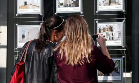 first-time-buyers look at home for sale in an agents window