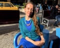 a woman wearing blue dress smiles while seated outside