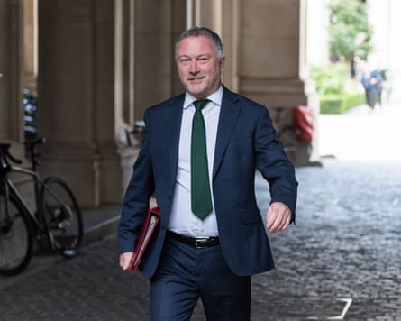 Steve Reed in a suit with a folder tucked under his arm walking along a cobbled alleyway.