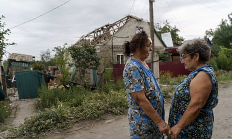 Valentyna Kondratieva, 75, left, is comforted by a neighbor as they stand outside her damaged home in Kramatorsk, Donetsk region, eastern Ukraine, after it was struck by rockets on Saturday (August 13)