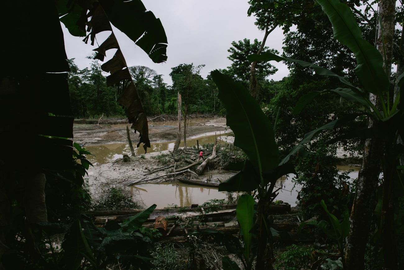 A woman walks in the destroyed land along the waterway of the Quebrada Pastacillo