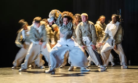 Blurred photograph of a group of hip-hop dancers with a female dancer at the centre looking at viewer