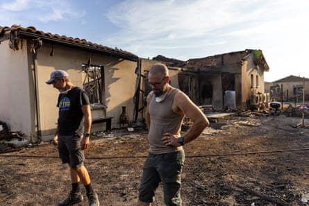 Two men stand amid ruined houses