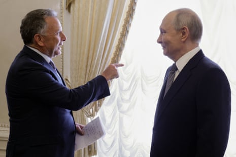 Steve Witkoff gestures while speaking to a smiling Vladimir Putin near a window