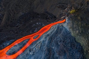 Overhead view of people standing near a flow of red lava