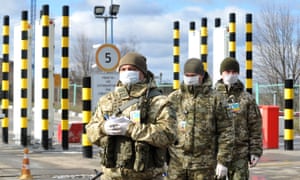 Ukrainian border guards wearing protective face masks are seen at the Goptivka checkpoint, near Kharkiv on the Ukrainian-Russian border, on March 16, 2020.