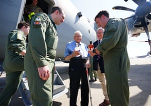 RAF veteran Dennis Bishop, aged 99, stands in front of a plane surrounded by crew members who are handing him some gifts at RAF Brize Norton in Oxfordshire UK