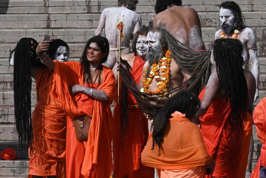 Naga sadhus (Hindu holy men and women) take pictures after taking a dip in the waters of the Ganges during Kumbh Mela in Haridwar.