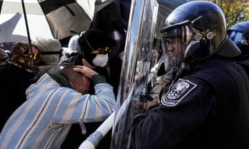 Police with shields and armor face off against protesters.