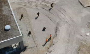 Still from drone footage shows men in military-style gear moving in formation while holding weapons at a former barracks in Mosbach
