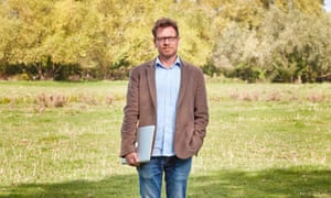 James Suzman holding a laptop and standing in a field