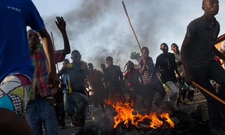 Protesters run across a fire towards police lines in the Musaga neighbourhood of Bujumbura, on Monday.