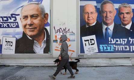 A man walks his dog between election campaign billboards for Benjamin Netanyahu (L) and Benny Gantz in Tel Aviv.