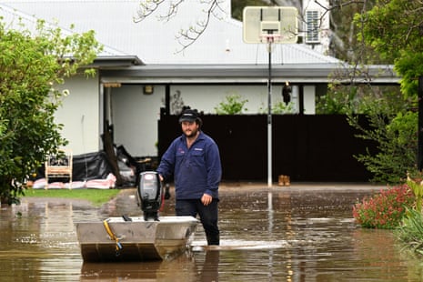 A man pushes a boat as flood waters inundate a residential area amidst evacuation orders in the Victorian town of Rochester.