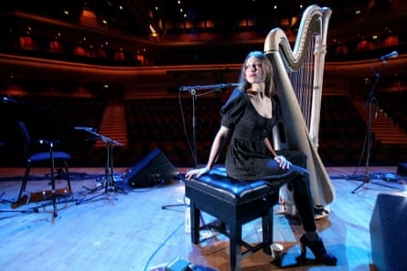 Newsom on stage in an empty auditorium, with a harp