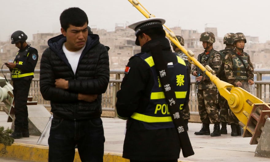 A police officer checks the identity card of a man as security forces keep watch in a street in Kashgar.