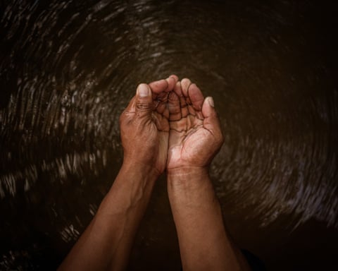 Cupped hands full of water above a body of water