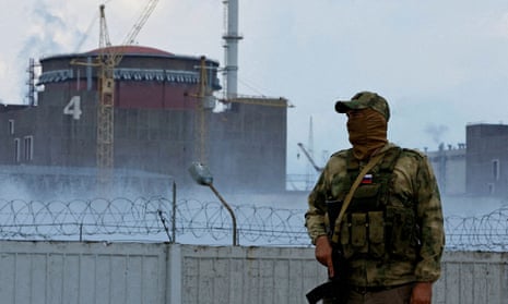 A man with a Russian flag on his uniform stands guard near the Zaporizhzhia nuclear power plant.
