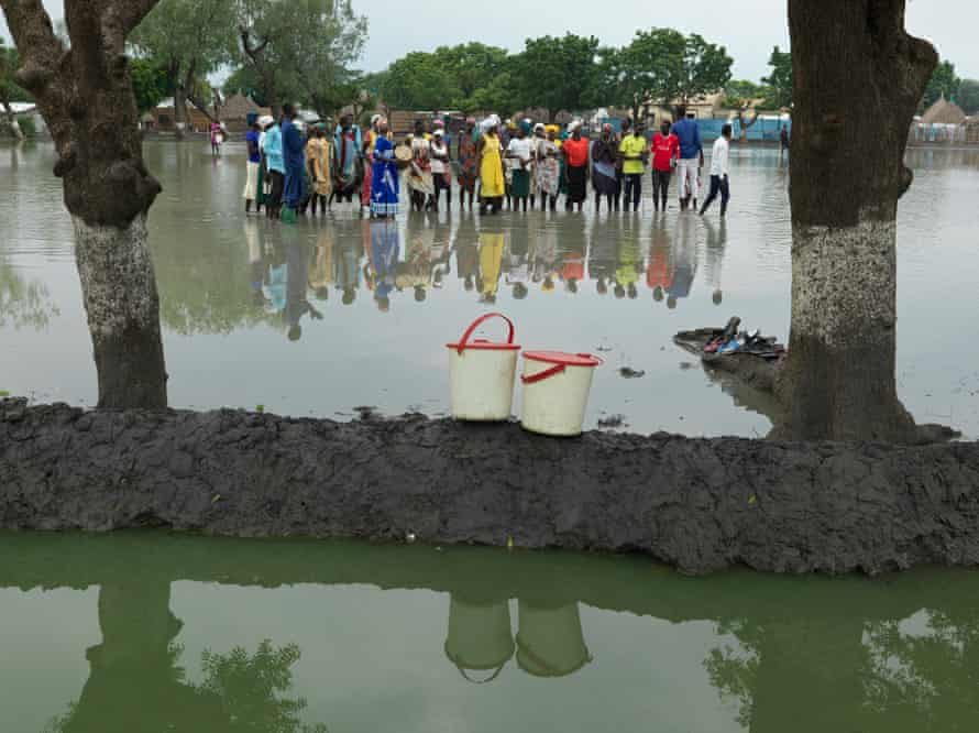 A church congregation stand on a flooded football pitch to sing and pray for an end to the flooding in Old Fangak.