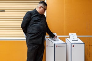 A man dressed as North Korean leader Kim Jong-un and wearing a pinstripe suit and sunglasses places his ballot paper into a cardboard box at a voting centre