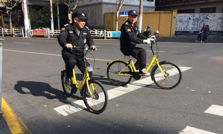 Security guards in Shanghai ride Ofo share bikes.
