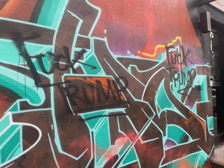 Black graffiti that says ‘Fuck Trump’ over other graffiti words
