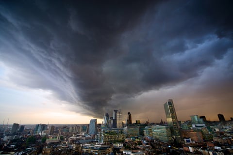 An evening storm, bringing torrential rain, casts an eerie light over the growing number of high-rise buildings that dominate the City of London skyline. 