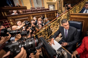 Sánchez, sits surrounded by photographers and cameras