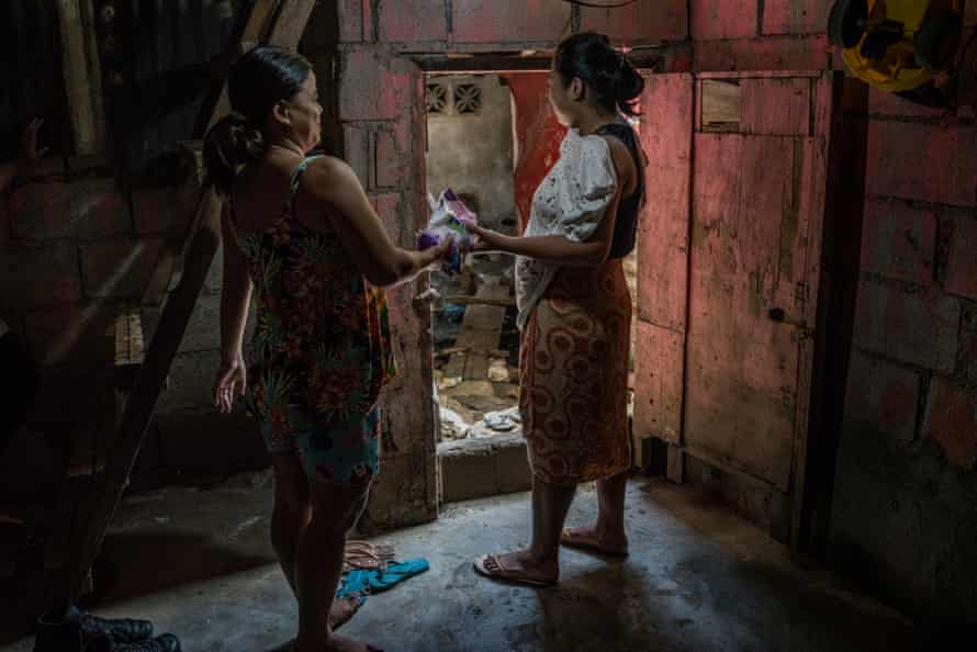 Rhoda hands over an Avon purchase to her neighbour, as her business has begun to slowly expand, on the first floor of her house, she was forced to abandon due to recurring flooding.