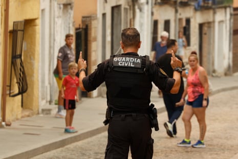 Um oficial de segurança fala com pessoas na rua.