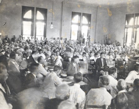 William Jennings Bryan, leaning over the table at left, speaking with Clarence Darrow, seated, in the crowded courtroom in 1925