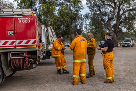 Members of a fire brigade rest next to a fire truck
