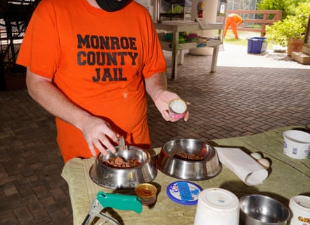 A then-inmate in orange prison uniform prepares food for the foxes at the Monroe County detention center’s zoo in July 2021