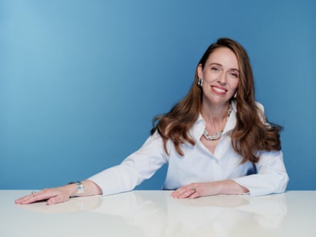 Jacinda Ardern sat at a desk wearing a white top.