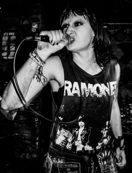 A singer in a Ramones tank top grimaces as she sings into the microphone