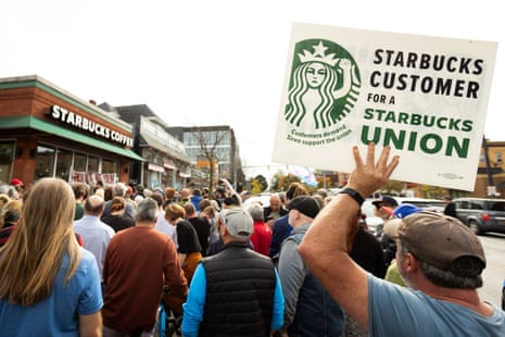 A large crowd outside a Starbucks location with one person holding a sign saying 'Starbucks customer for a Starbucks union'.