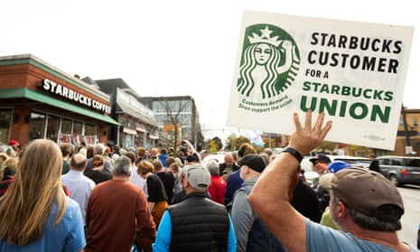 People gather outside a Starbucks location while singer Billy Bragg performs for striking Starbucks Workers United Union members in Buffalo, New York.