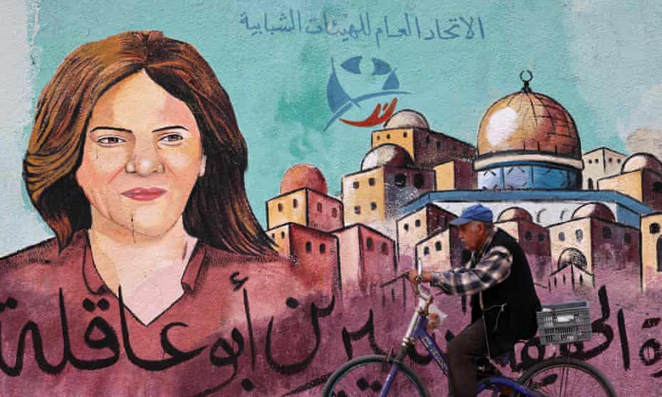 A Palestinian man cycles past a mural in honour Al-Jazeera journalist, Shireen Abu Aqleh, in Gaza City.