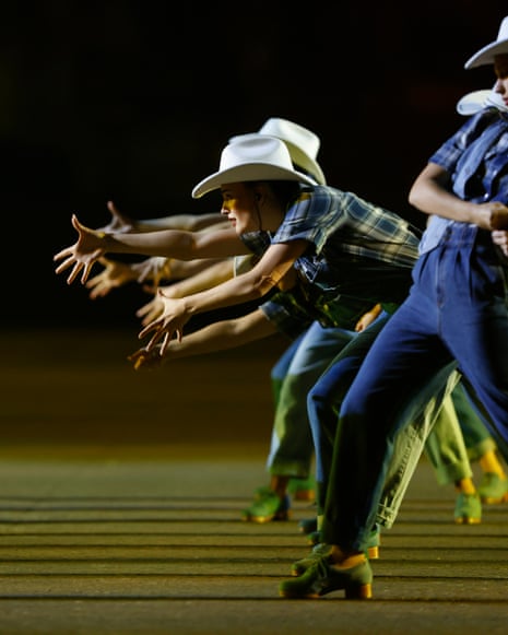 dramatic shot of dancers reaching out across a divide wearing cowgirl gear and stetsons
