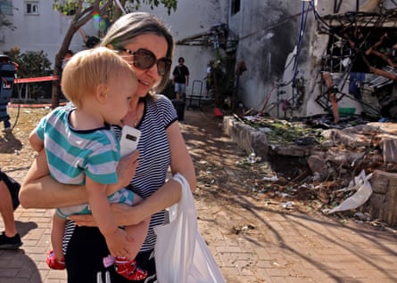 A woman carries her child outside a building which received a direct hit by rockets from the Gaza Strip, in the southern Israeli city of Ashdod on Monday.