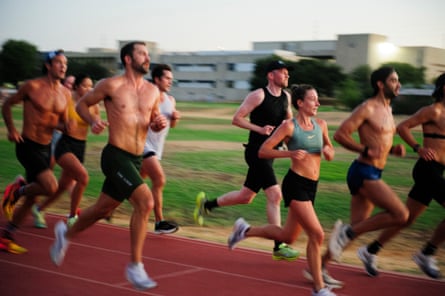 people run on track against a sky that’s getting lighter