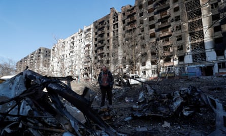 A local resident stands next to the wreckage of his car in the courtyard of a burnt-out apartment block in Mariupol, Ukraine.