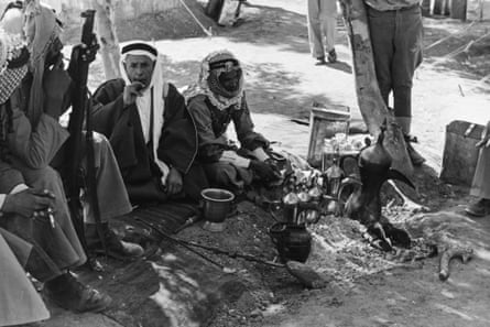 Men of the Arab Legion in Transjordan smoke cigarettes outside near a row of urns in 1941.