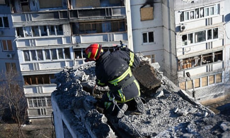 A rescue worker removes debris from a residential building partially destroyed by shelling on the outskirts of Kharkiv.