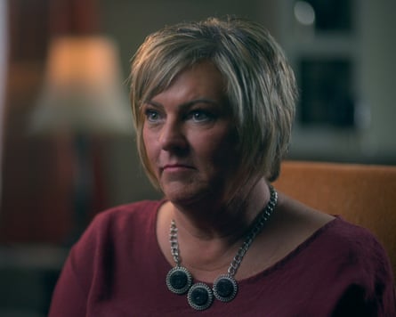 Shawna with short blond hair wearing a burgundy top and circular pendant necklace looks to the side