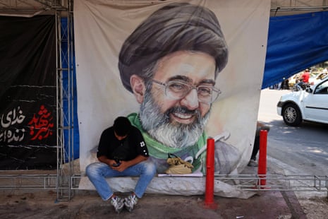 A man sits in front of a poster with portrait of Iranian supreme leader Mojtaba Khamenei, at the Vanak Square in Tehran on 10 June 2026.