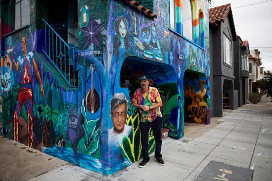 Richard Segovia stands in front of his colorfully painted home in San Francisco. The house next to his has been painted gray.