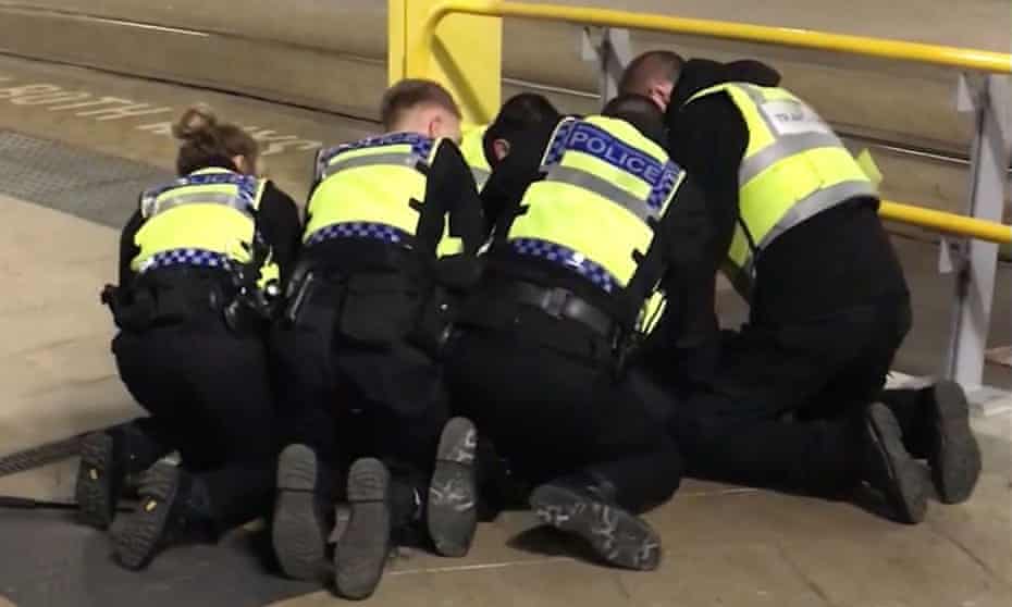 Police restrain a man after three people were stabbed at Victoria Station in Manchester on New Year’s Eve.
