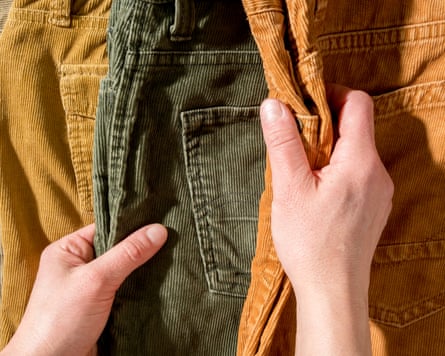 Hands touch the corduroy trousers lying on the counter